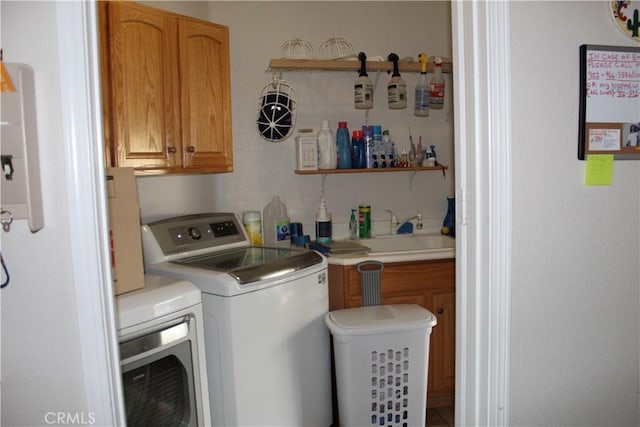 laundry area featuring cabinet space, washer and clothes dryer, and a sink