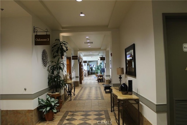 hallway featuring recessed lighting and a raised ceiling