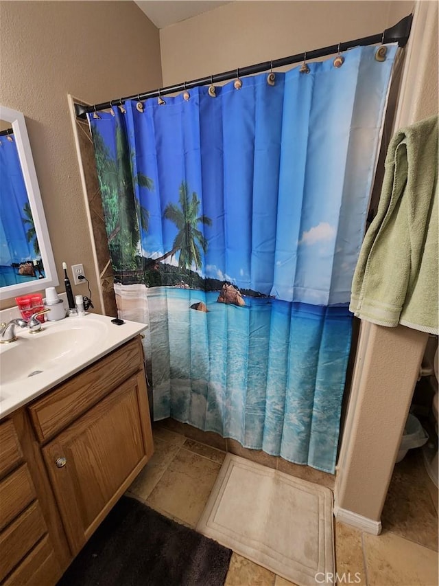 bathroom featuring a textured wall, vanity, and a shower with shower curtain