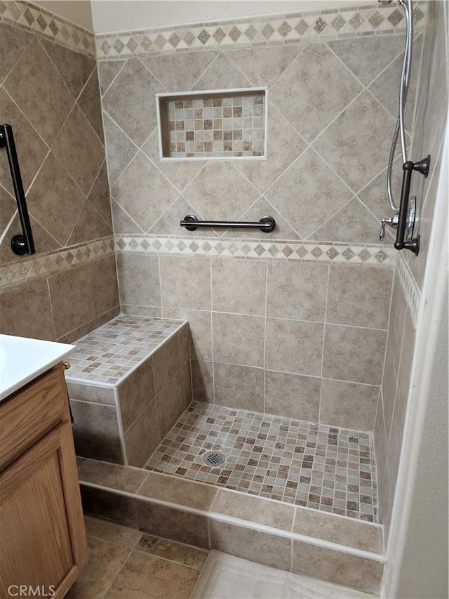 full bathroom with tiled shower and vanity