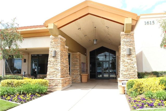 view of exterior entry featuring stucco siding, stone siding, and french doors