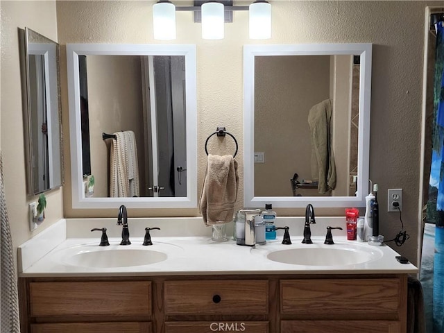 full bathroom featuring double vanity, a sink, and a textured wall