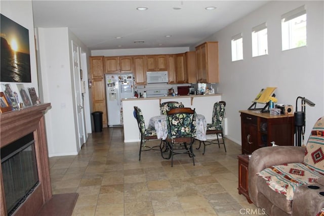kitchen featuring recessed lighting, a peninsula, white appliances, baseboards, and a glass covered fireplace
