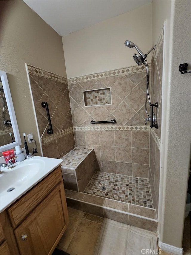 full bath with a tile shower and vanity