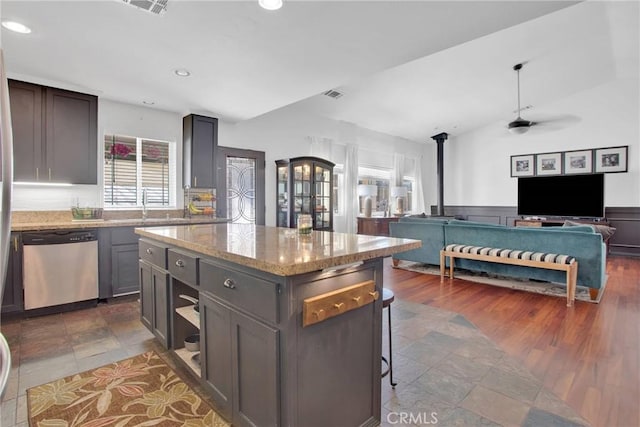 kitchen with lofted ceiling, stainless steel dishwasher, a wainscoted wall, visible vents, and ceiling fan