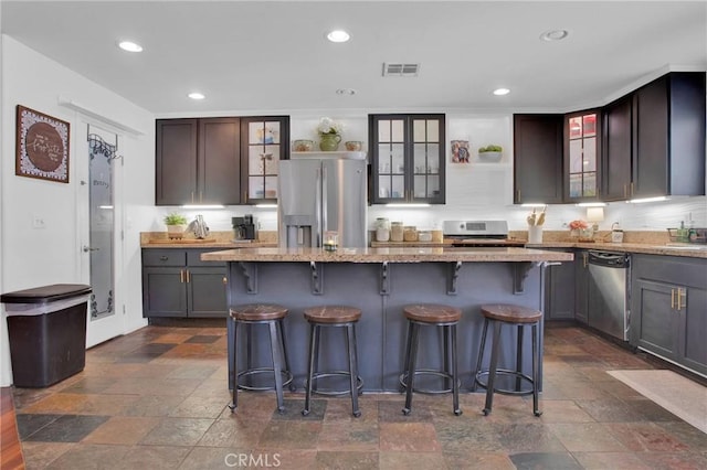 7575 Rancho Rd, Wrightwood, CA 92372 - kitchen with appliances with stainless steel finishes, open shelves, stone tile flooring, glass insert cabinets, and light stone counters