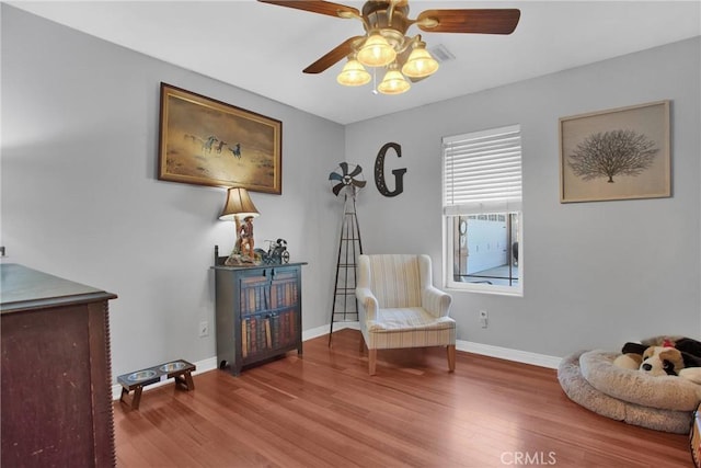 sitting room featuring baseboards, visible vents, wood finished floors, and a ceiling fan