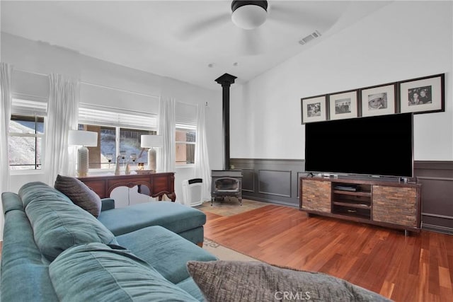 7575 Rancho Rd, Wrightwood, CA 92372 - living area with wood finished floors, a wood stove, ceiling fan, wainscoting, and a decorative wall