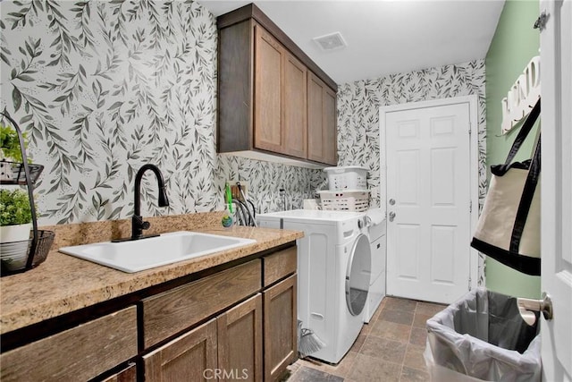 clothes washing area with wallpapered walls, a sink, visible vents, cabinet space, and washing machine and dryer