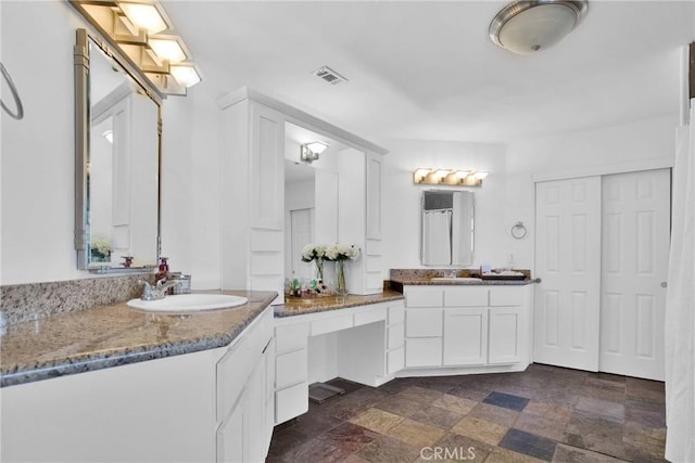 full bath with vanity, stone finish flooring, and visible vents