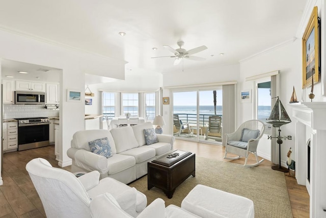 living area with ornamental molding, ceiling fan, and wood finished floors