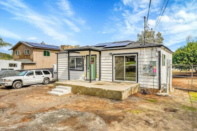 view of front of house with roof mounted solar panels and fence