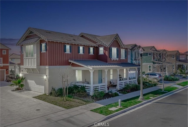 townhome / multi-family property with metal roof, a porch, a residential view, stucco siding, and board and batten siding