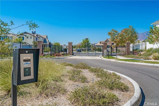 view of street with a gate, curbs, sidewalks, and a gated entry