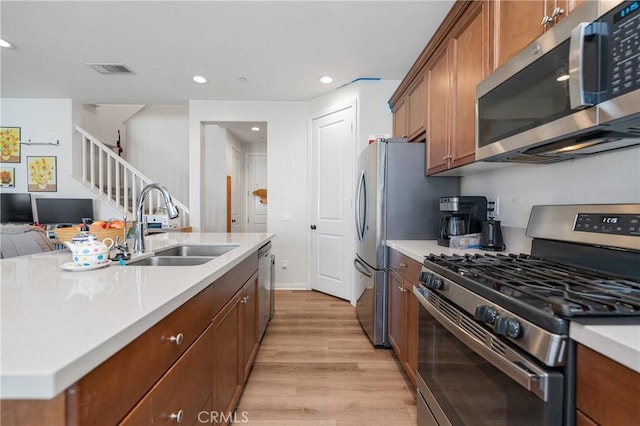 kitchen with stainless steel appliances, a sink, visible vents, and brown cabinets