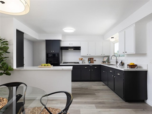 kitchen featuring stainless steel gas cooktop, oven, light countertops, white cabinetry, and a sink