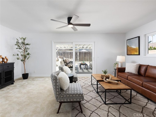 carpeted living area with ceiling fan and baseboards