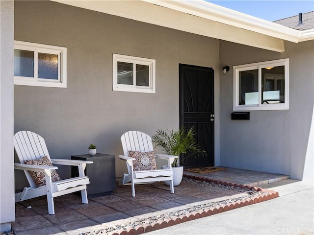 view of exterior entry with a patio area and stucco siding