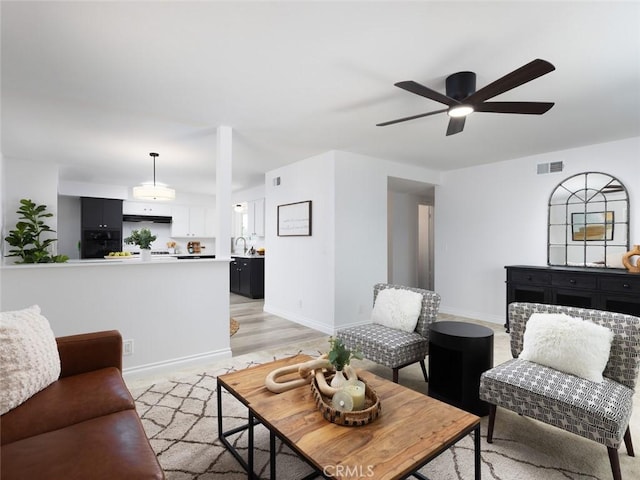 living room featuring visible vents, ceiling fan, and baseboards