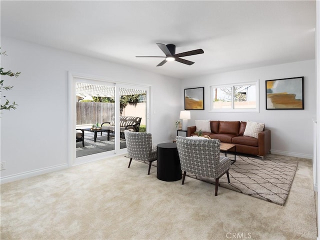 living area featuring a ceiling fan, carpet, and baseboards