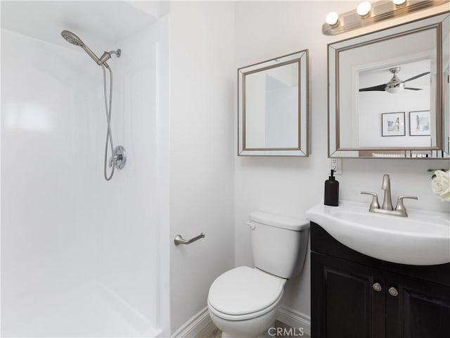 bathroom featuring ceiling fan, toilet, vanity, baseboards, and walk in shower