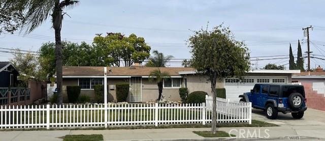 single story home featuring a garage, a fenced front yard, and concrete driveway