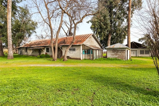 rear view of property featuring metal roof and a yard