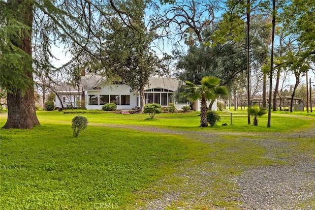 view of yard with driveway and a sunroom