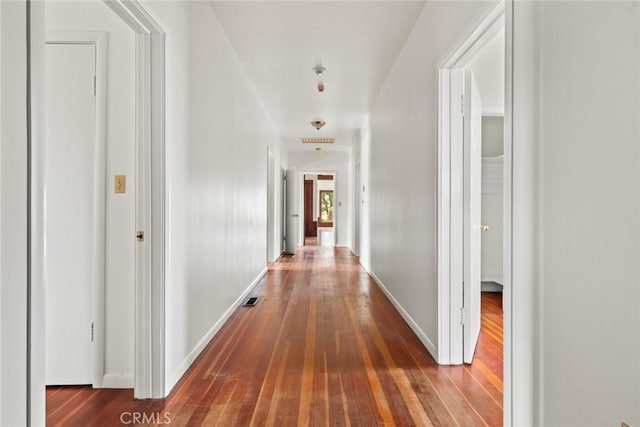 hall featuring dark wood-type flooring and baseboards