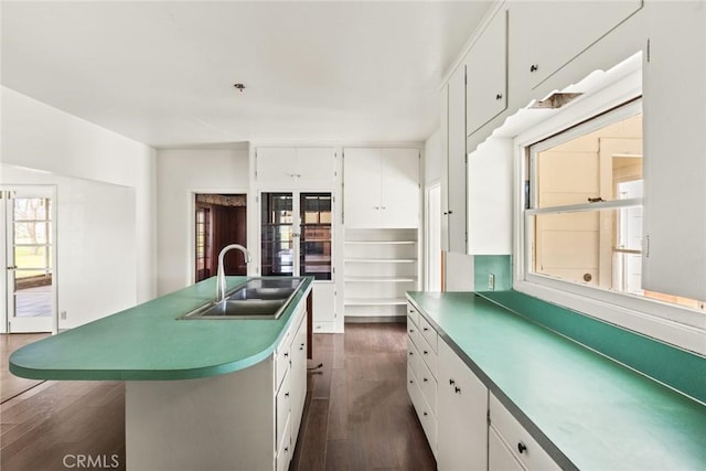 kitchen featuring dark wood-style floors, a center island with sink, white cabinetry, and a sink