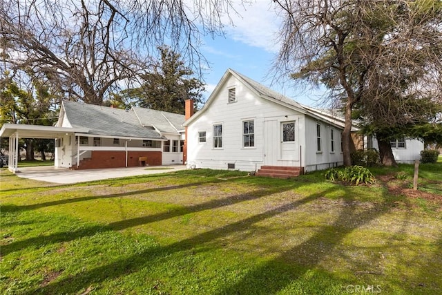 back of house with a carport, entry steps, crawl space, and a lawn