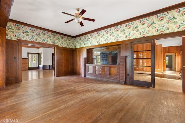 unfurnished living room with ornamental molding, a ceiling fan, and wood finished floors