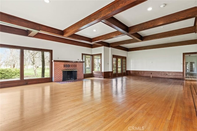 unfurnished living room with french doors, a fireplace, wood-type flooring, wainscoting, and beamed ceiling