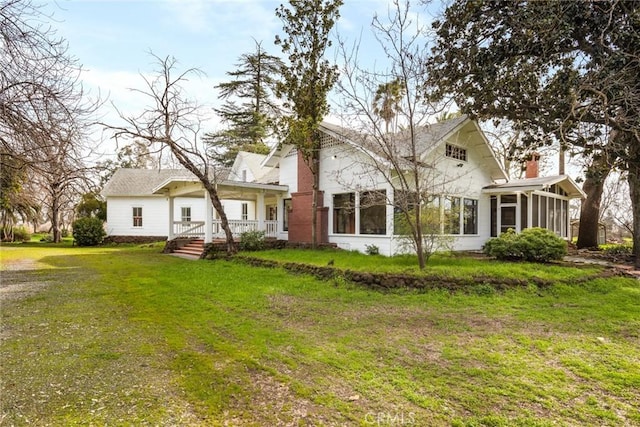 rear view of house with a lawn, a chimney, and a sunroom