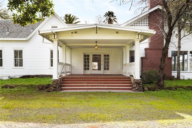 view of exterior entry with a porch and a lawn