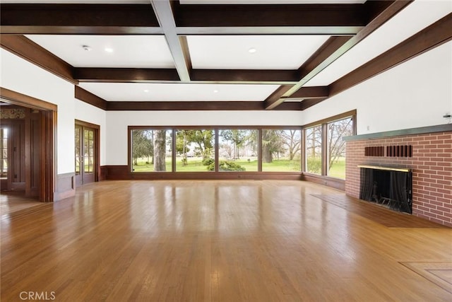 unfurnished living room featuring a wealth of natural light, a brick fireplace, coffered ceiling, and beam ceiling