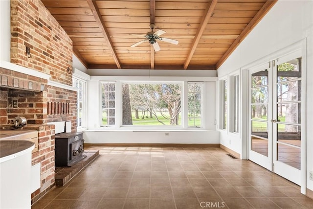 unfurnished sunroom featuring visible vents, wooden ceiling, ceiling fan, a wood stove, and vaulted ceiling with beams