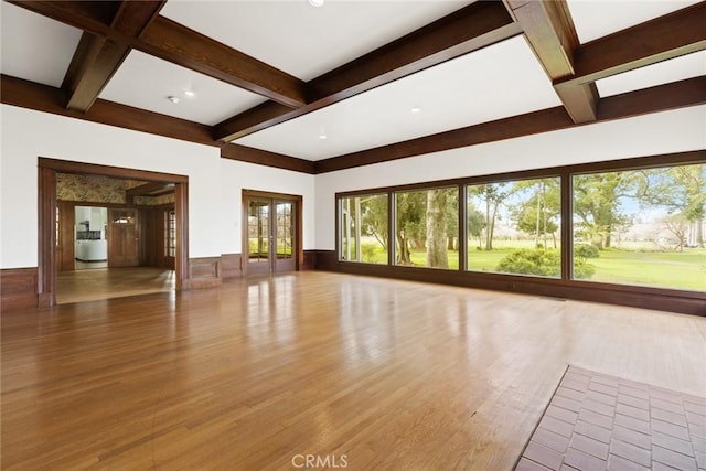 unfurnished living room with beam ceiling, coffered ceiling, wood finished floors, and french doors