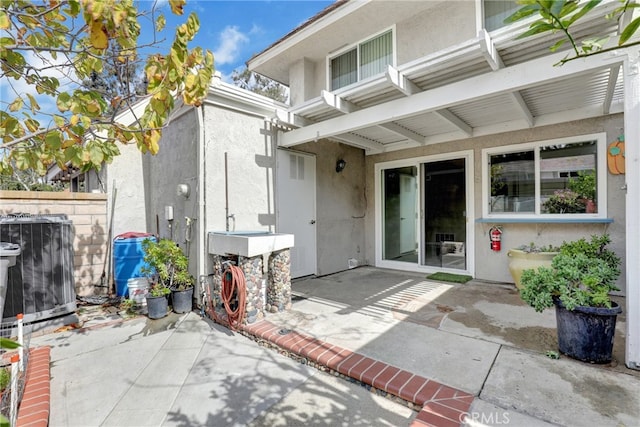 exterior space with a patio area, central AC, and stucco siding