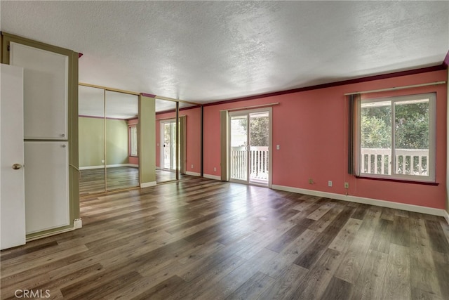 empty room with a textured ceiling, wood finished floors, and baseboards