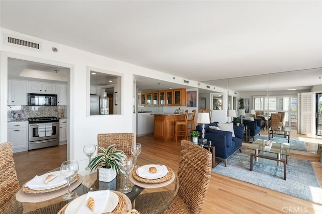 dining space featuring light wood-style floors and visible vents