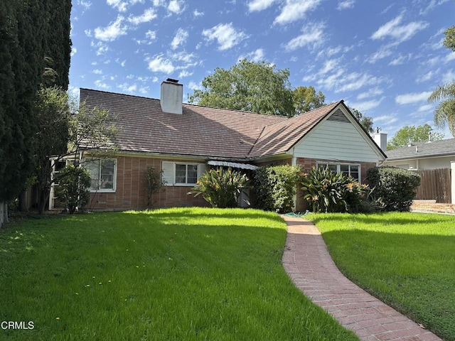 view of front of property with a chimney, a front lawn, and brick siding