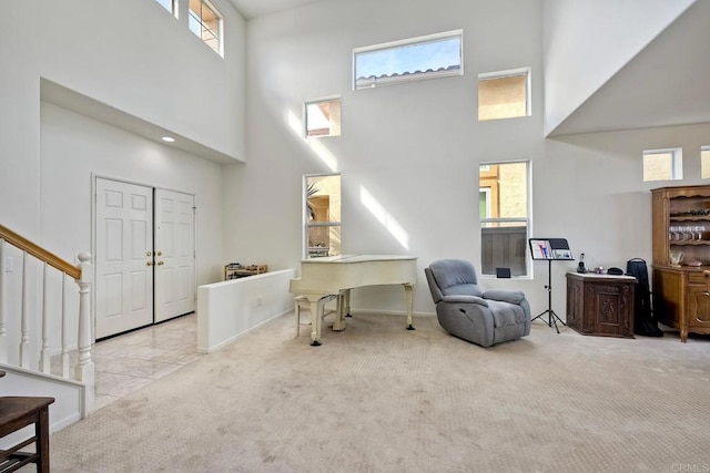 living area with stairway, carpet, a towering ceiling, and baseboards