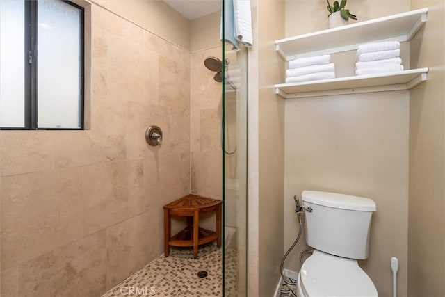 bathroom with toilet and a tile shower