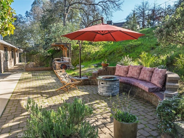 view of patio featuring an outdoor fire pit and an outdoor stone fireplace