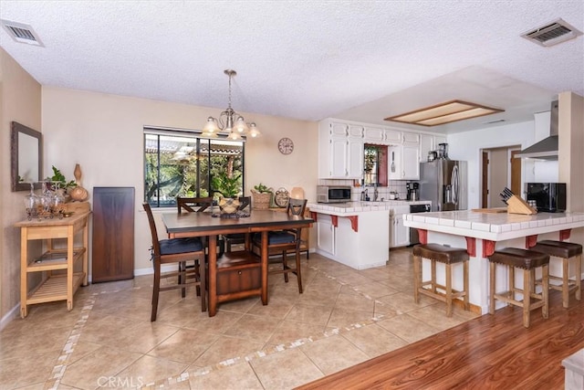 dining room with light tile patterned floors, a textured ceiling, a chandelier, and visible vents