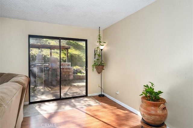 entryway with a textured ceiling, baseboards, and wood finished floors