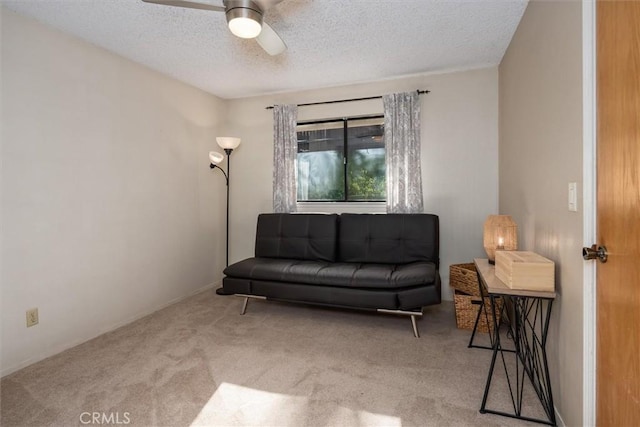 sitting room with a textured ceiling, carpet floors, and a ceiling fan