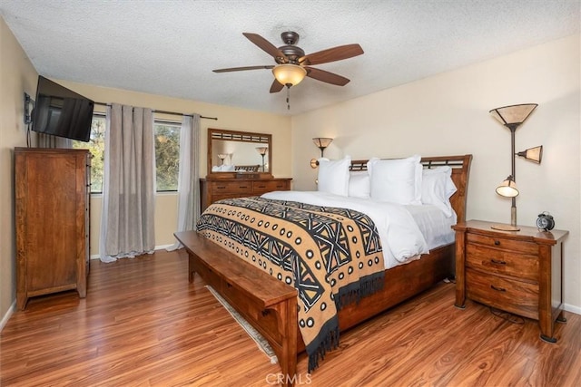 bedroom featuring baseboards, a textured ceiling, a ceiling fan, and wood finished floors