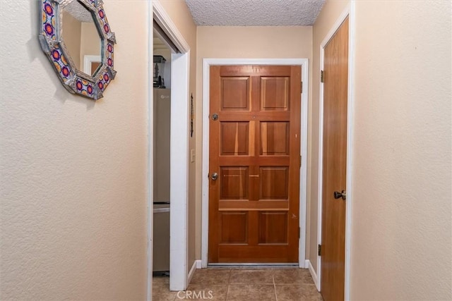 doorway to outside with a textured ceiling and tile patterned floors